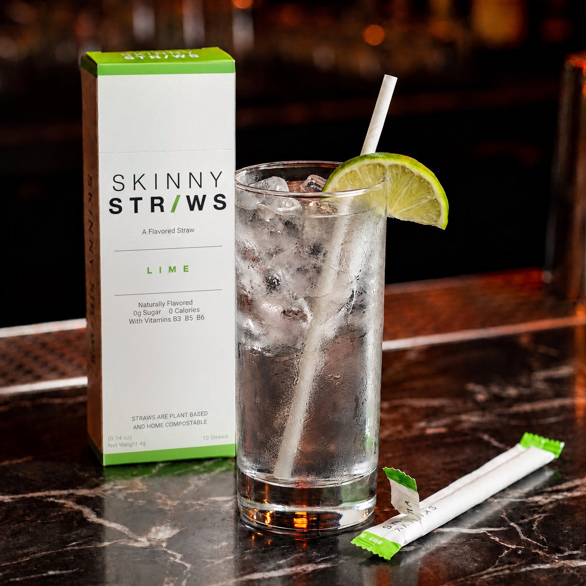 Vodka soda with a Skinny Straws flavored straw beside the Lime box at a bar